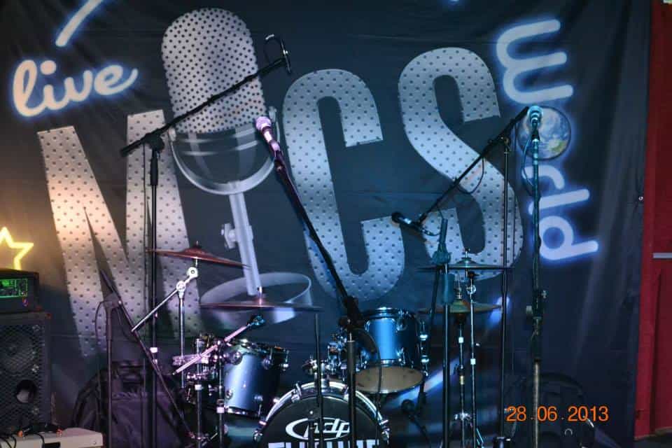 Microphone and drum set on stage for live music performance.